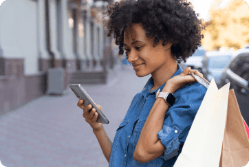 An image of a lady looking at her phone while smiling.